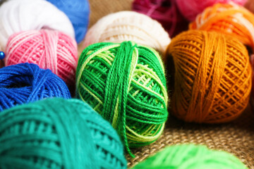Balls of yarns on burlap fabric, closeup