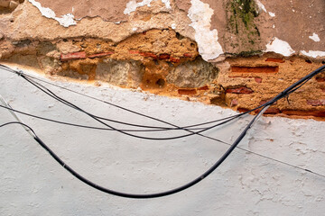 Exposed Wires and Peeling Plaster on an Old Urban Wall