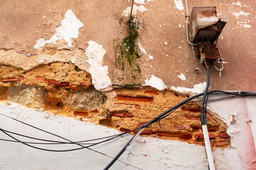 Weathered Urban Wall with Exposed Wires and Crumbling Plaster