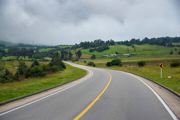 Two-lane road in a Colombian countryside on a cloudy day.