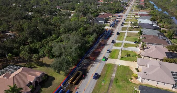 One-lane traffic flows through Florida neighborhood street as crews dig trenches for wastewater pipes beneath the roadside.