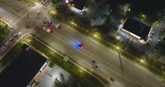 Police car with flashing lights pulled over a speeding vehicle at night on a busy city street in the USA. Urban traffic passing during traffic stop.