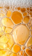 Close-up abstract view of golden liquid with various sized bubbles and foam, creating a textured surface.