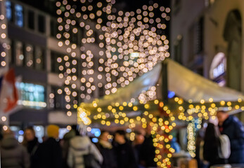 Twinkling festive lights illuminate Rennweg street in Zurich, Switzerland, casting a glow on historic buildings during Chrsitmas markets, bokeh blur