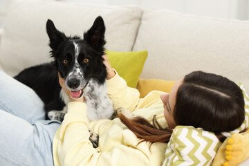 Woman with her cute Border Collie dog on sofa at home