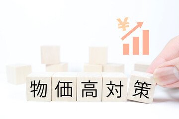 物価高対策を示す木製ブロックと円マークの上昇グラフ。
