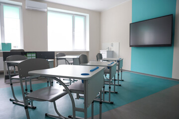Stylish classroom with desks, chairs and tv at school