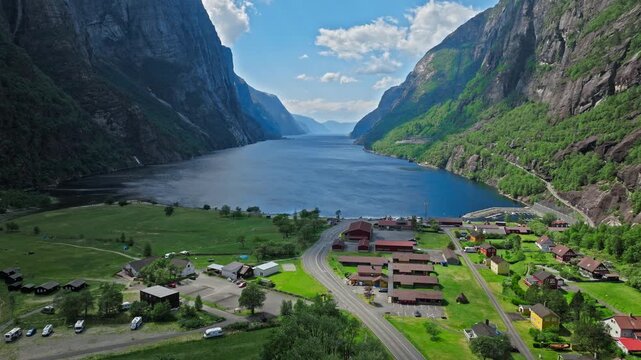 Aerial view looking toward Lysefjord from Lysebotn village, Norway. Fjord water stretches between steep mountains with homes and roads in the foreground.