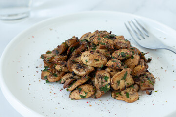 Spicy mushrooms in a plate on white kitchen table. Close-up.