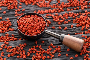 Bixa Orellana - Organic red annatto seeds on a measuring spoon and scattered on the bottom