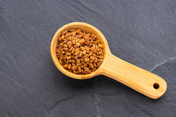 Methi Dana - Dried organic fenugreek seeds in the wooden spoon