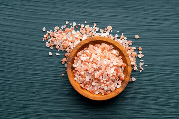 Himalayan salt crystals in a wooden bowl on a green background - Exotic ingredient for cooking