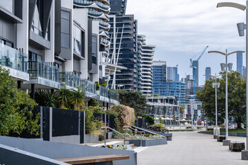 Contemporary townhouses, apartment buildings, landscaped terraces, and wide pedestrian walkways in Docklands, Melbourne, Australia. Real estate, high-density living, and inner-city neighborhoods.