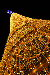 A Christmas tree frame made of golden lights from garlands against the night sky