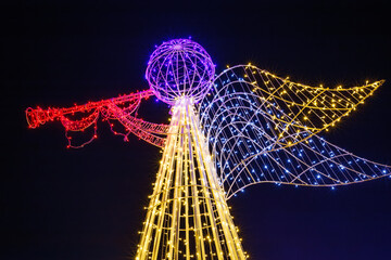 Illuminated angel sculpture with trumpet at night