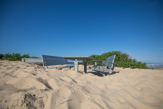 Tables and chairs at the beach buried in deep sand after storms