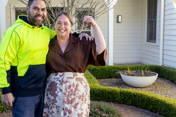 Mixed ethnicity couple showing keys of their new home