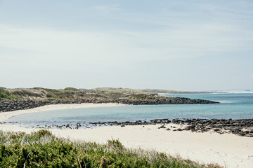 Calm flat blue ocean and beach with sand and rocks