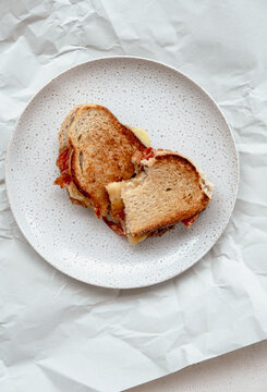 Toasted sandwich partly eaten on a plate.