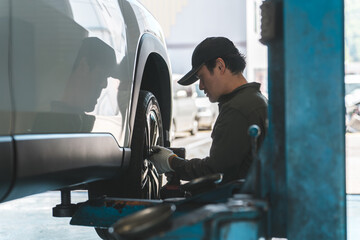 A male mechanic changing the tire on a lifted car