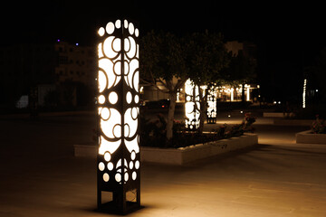 Modern decorative light posts illuminate a night plaza