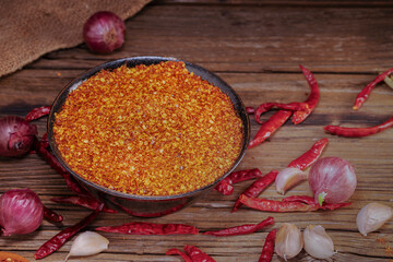 Close up of Asian seasoning chili powder in black bowl. Spicy condiment and spices, shallots, garlic for cooking. Top view.