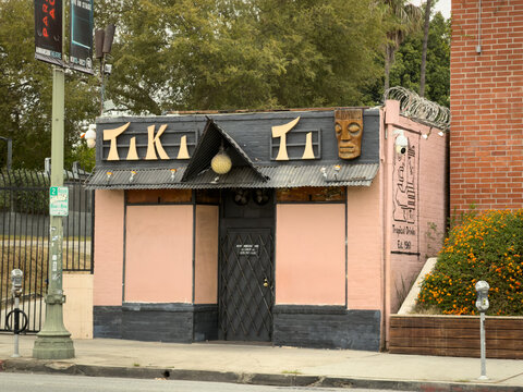 LOS ANGELES, CA, OCT 7, 2025: Pink and black Tiki bar building in Hollywood, with boarded windows, tropical decorations including masks and pineapple, sign reads "Tiki Ti" and Tropical Drinks Est. 196