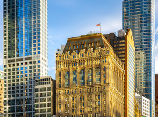 Historic skyscraper in downtown Manhattan with ornate facade under warm sunlight