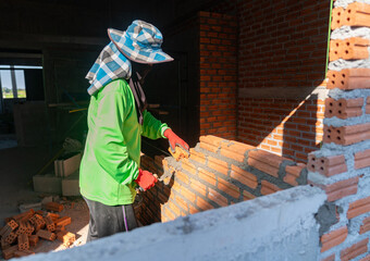 Skilled bricklayer constructing a brick wall with mortar and trowel.