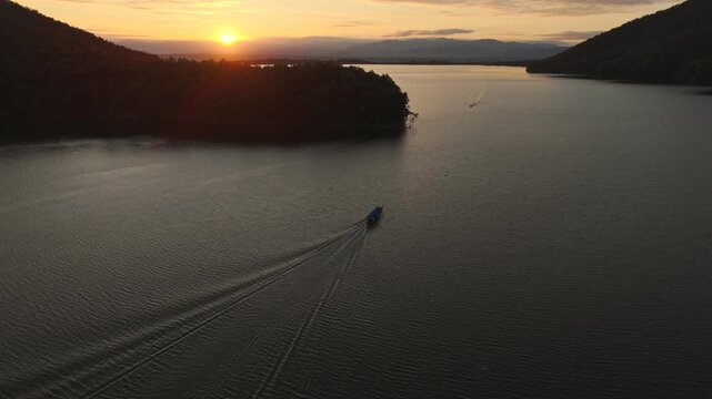 Drone shot of boat on calm lake with sunset reflection