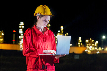Petrochemical industry night engineer man and woman teamwork working on laptop at night. Engineer technician working overtime with labtop at refinery construction plant  for transportation.