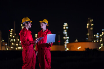 Petrochemical industry night engineer man and woman teamwork working on laptop at night. Engineer technician working overtime with labtop at refinery construction plant.