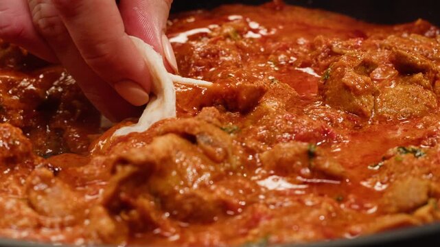 Cooking chicken Indian curry, tikka masala, chicken, lamb, mutton Rogan Josh grill boiling on pan, sauce. Dark background. Close up.