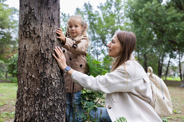 Naklejka premium Mother and daughter exploring tree bark together in a green park