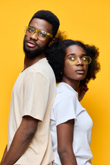 Obraz premium Stylish young couple with glasses against a vibrant yellow background, expressing confidence and joy, perfect for modern fashion and lifestyle concepts