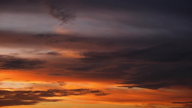A sunrise sky time-lapse video showcasing layered altostratus and stratocumulus clouds, glowing in golden and amber hues as they drift smoothly, creating rich textures and a early-morning atmosphere.
