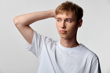 Man with puzzled expression, hand on head, casual white tee, studio lighting, conveying confusion and contemplation for thinking, decision making, problem solving, and everyday uncertainty