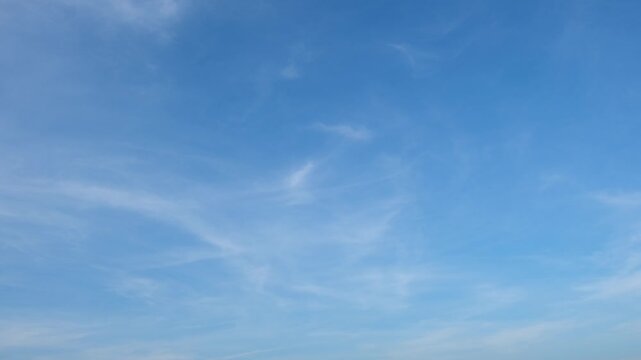 Blue sky timelapse video with thin cirrus and wispy cirrostratus clouds gently stretching and shifting, revealing smooth atmospheric flow, calm weather patterns, and serene daytime skies. Time-lapse.
