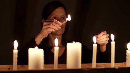 Woman Lights Candles in Dark Room: Warm Illumination for Rituals and Celebrations