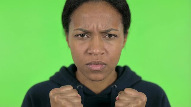 Close up Portrait Of An Angry Young Black Woman Clenched Fists Screaming Frustrated Emotion On Green Screen Background Studio Lighting