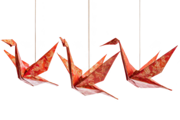 Three origami cranes made of red paper with gold patterns hanging on strings