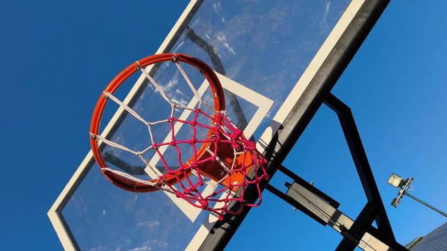 Street Basketball Hoop Under Blue Sky. Outdoor Basketball Hoop on Urban Street. Urban Basketball Backboard Against Blue Sky. Empty Street Basketball Hoop in Daylight.