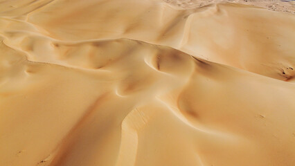 Expansive aerial perspective of rolling orange sand dunes in the Liwa Desert, Empty Quarter, UAE. Beautiful natural patterns and desert landscape under a clear sky © Anton Gots