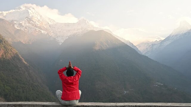 Rear view of young woman doing Yoga in the morning with beautiful with of Mt.Annapurna south with Mt.Machapuchare seen from Chomrong village in Nepal.