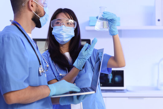 Young doctors with laptop and flask analyzing scientific data in laboratory - Powered by Adobe