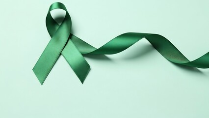 Symbol of hope: a lustrous emerald green satin ribbon tied in a loop, representing awareness and support for various causes.