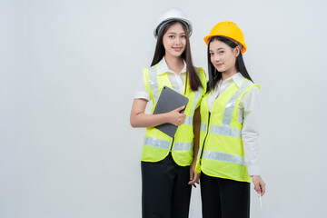 Asian female engineers in safety helmets analyze digital project information, symbolizing smart construction ecosystems, future industry skills, collaboration, and modern engineering professionalism.