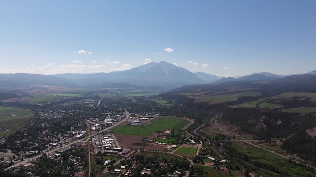 High panoramic descend from Mushroom Rock, Carbondale valley, residential neighborhoods, winding roads, green foothills, and dramatic Mount Sopris rising in the background
