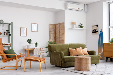 Obraz premium Interior of living room with surfboard, green sofa and armchair