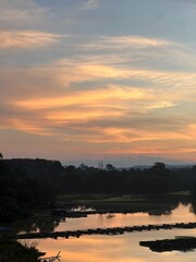 Naklejka premium Serene Sunset Over Water Reflecting the Sky's Fiery Hues Amidst Silhouetted Trees